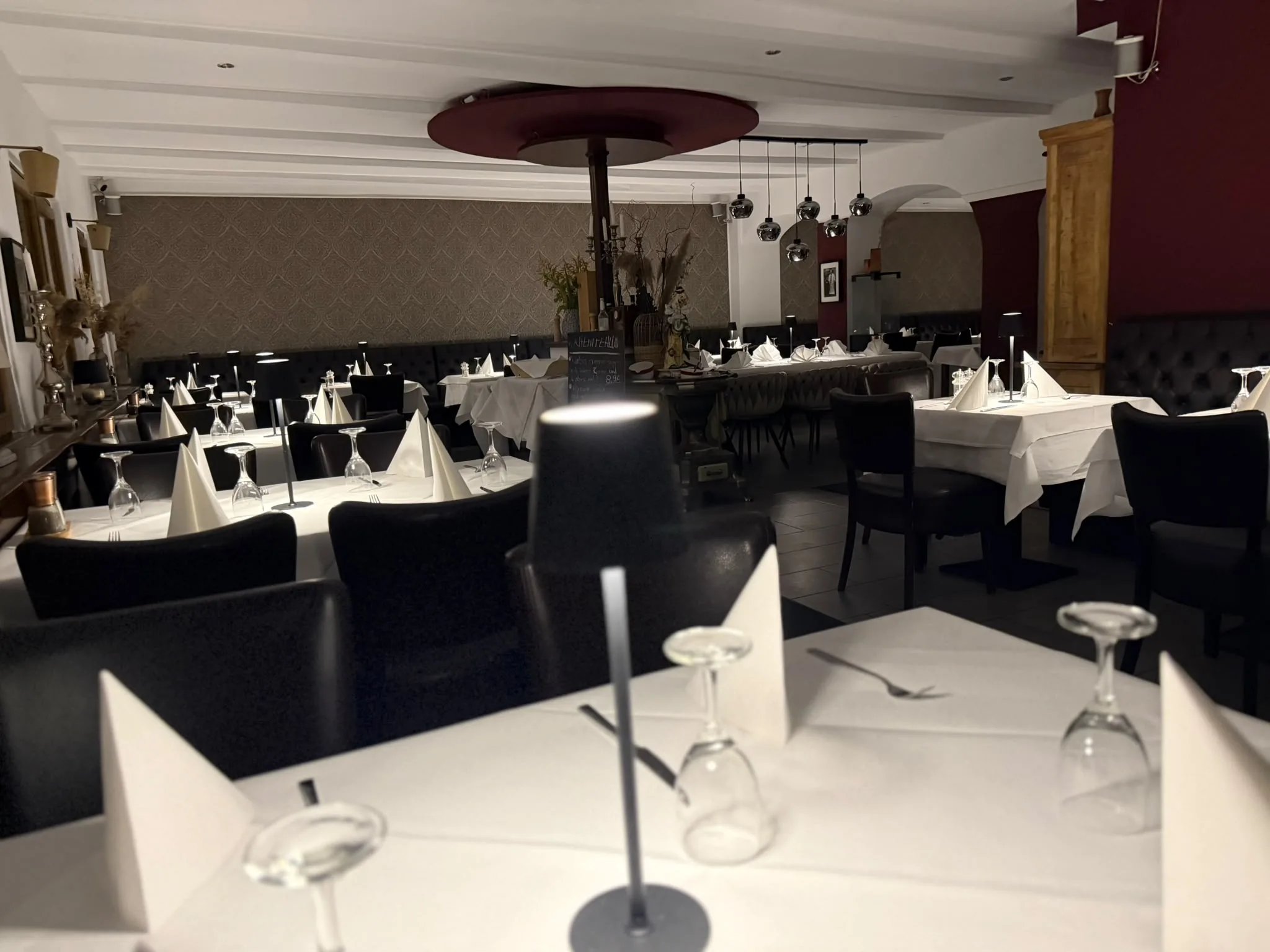 Gedeckte Tische mit Tischlampen im Gastraum am Abend